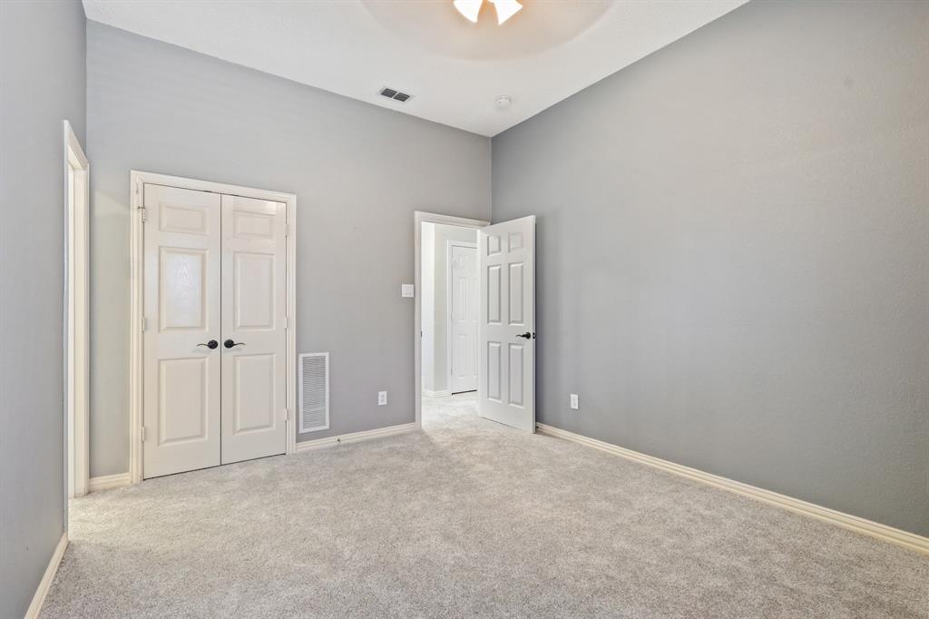 High-ceilinged room featuring neutral wall tones, plush wall-to-wall carpeting, and double-door closet cabinetry with matte black hardware