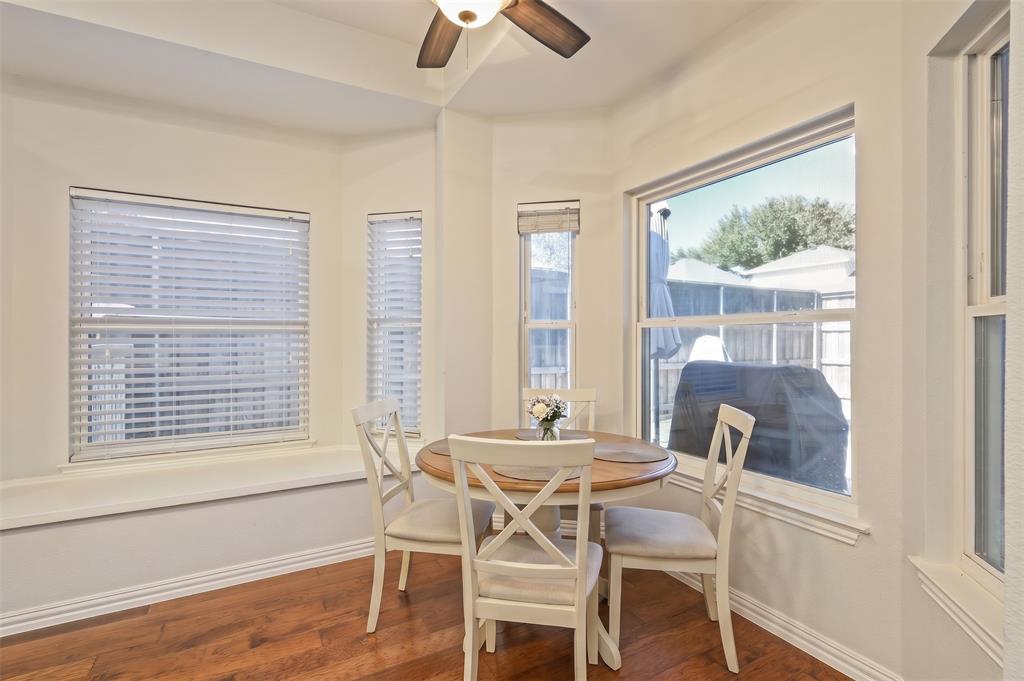 Bay window featuring an integrated ledge, wood-finish flooring, multi-pane windows with horizontal blinds, and a ceiling fan with light fixture