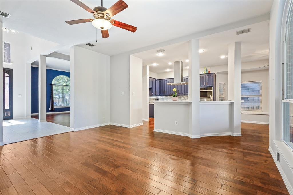 Open interior featuring wood-finish flooring, recessed lighting, a ceiling fan, and a kitchen equipped with a stainless steel range hood
