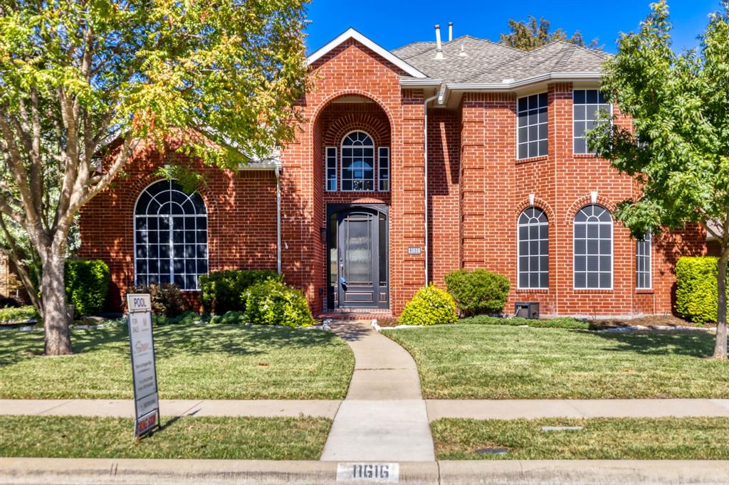 Red brick exterior featuring a recessed arched entryway, decorative arched windows, and a multi-gabled roofline