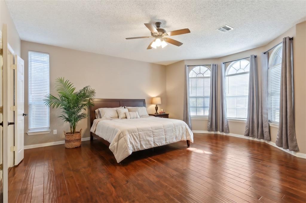 Wood-finish flooring, bay windows with arched transoms, and a central ceiling fan( virtually Staged)