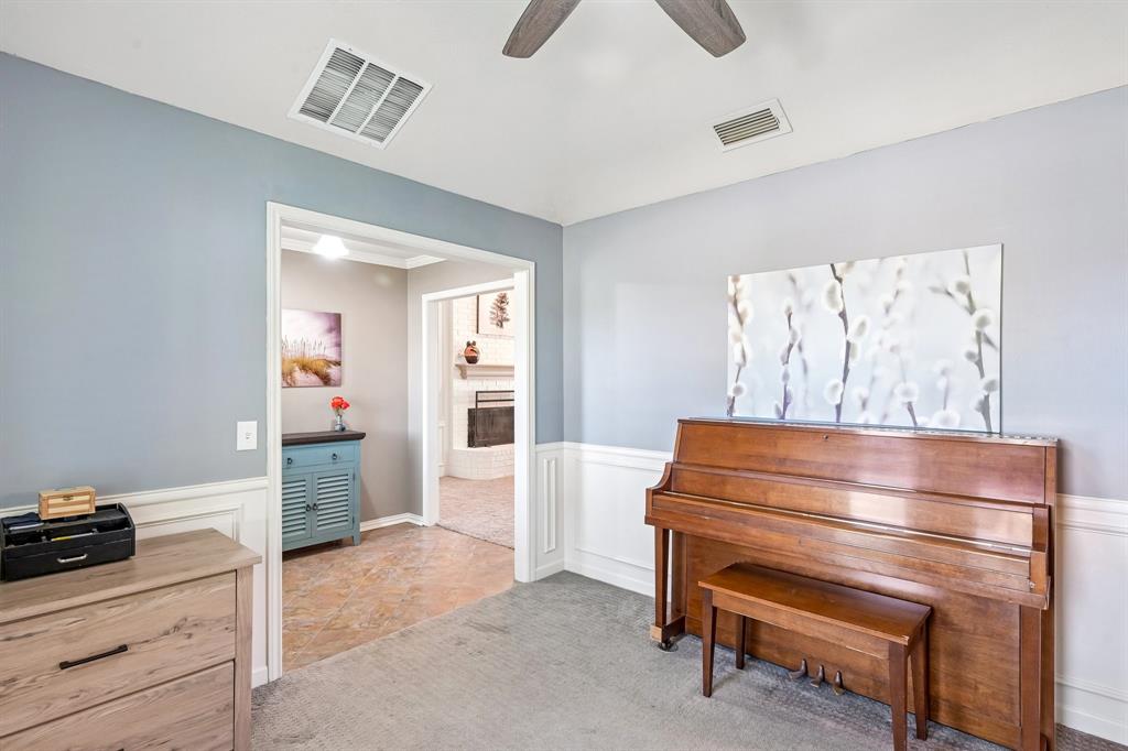 Carpeted room with wainscoting and light blue wall paint, featuring a ceiling fan