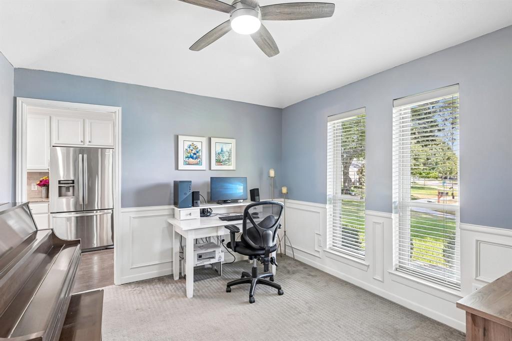 Bright interior space featuring a ceiling fan, dual large windows, and wainscoting