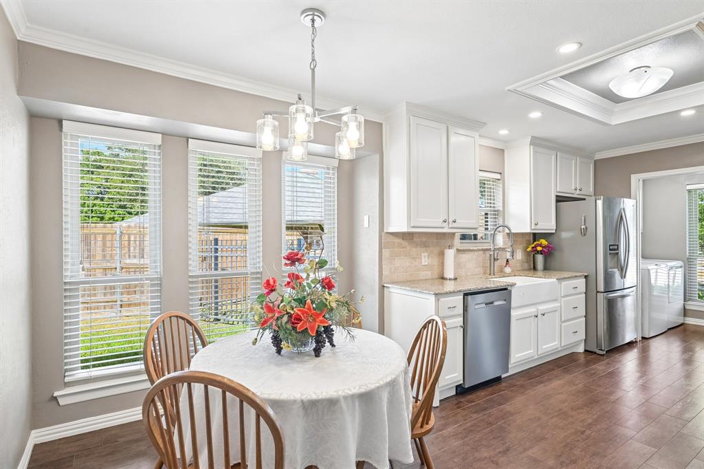 Kitchen with white shaker cabinetry, stainless steel appliances, a farmhouse sink, and wood-finish flooring