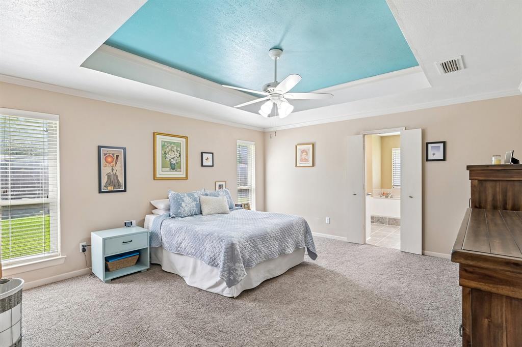 Tray ceiling with a textured finish, ceiling fan, and carpeted flooring