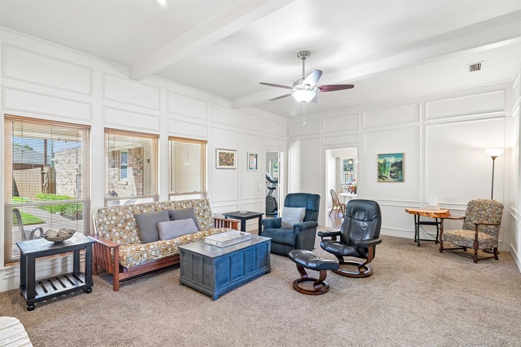 Expansive living space featuring wall paneling, a ceiling fan, carpet flooring, and multiple windows