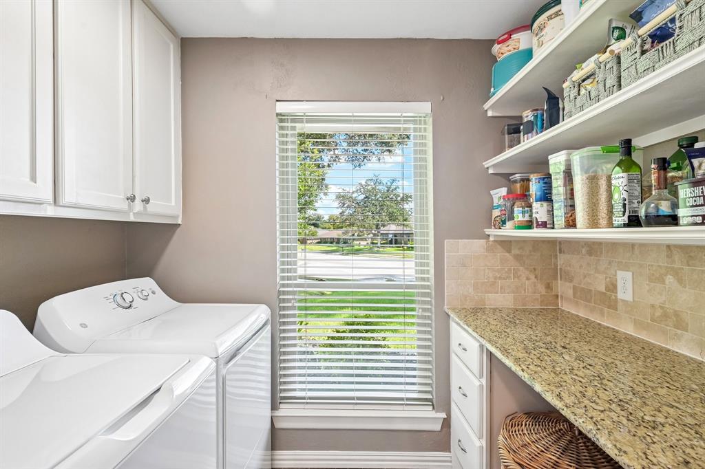 Built-in white cabinetry, granite-finish countertop, tiled backsplash, and open shelving