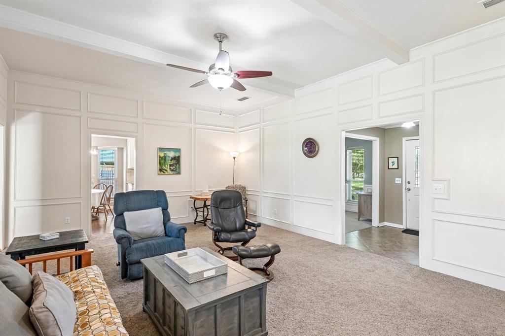 Coffered ceiling detail, decorative wall molding, ceiling fan, and carpet flooring