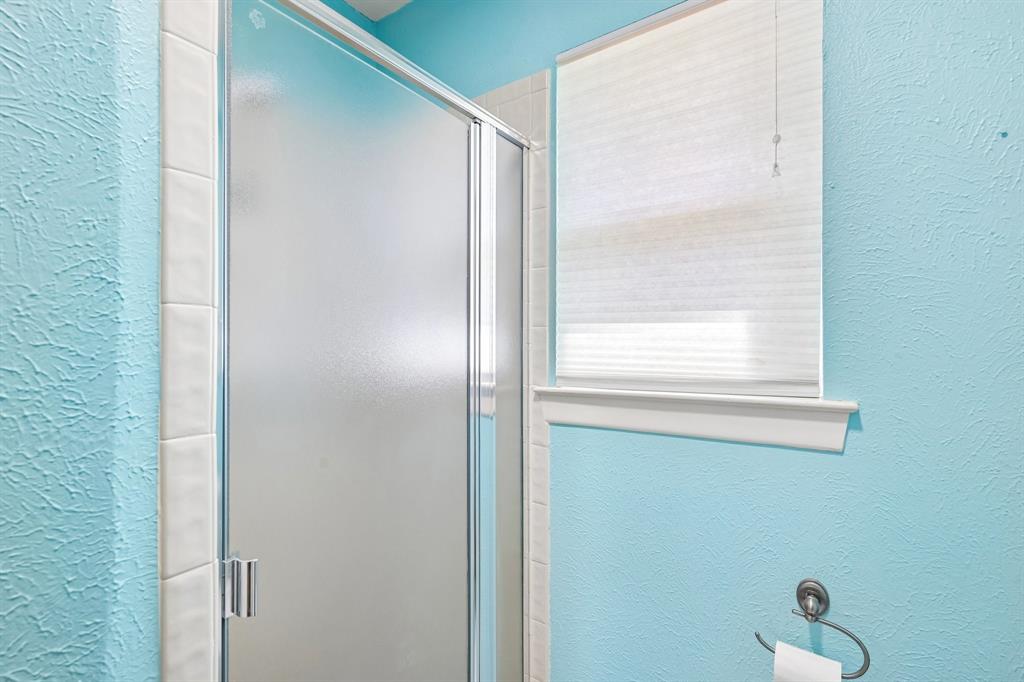 Frosted glass shower enclosure with chrome hardware, white tile surround, and textured blue walls