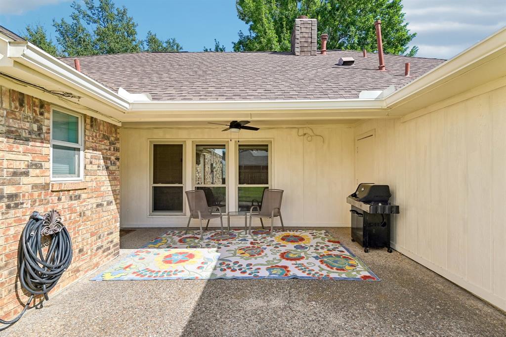 Covered patio featuring an outdoor ceiling fan, brick exterior, and a shingle roof
