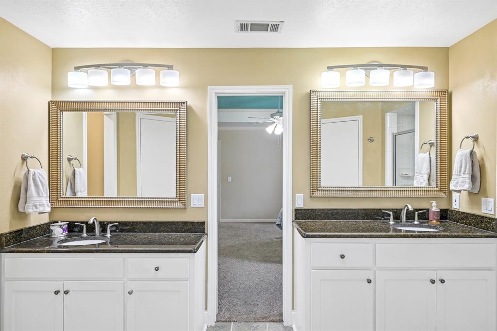 Dual vanity with white cabinetry, dark countertop, and individual framed mirrors