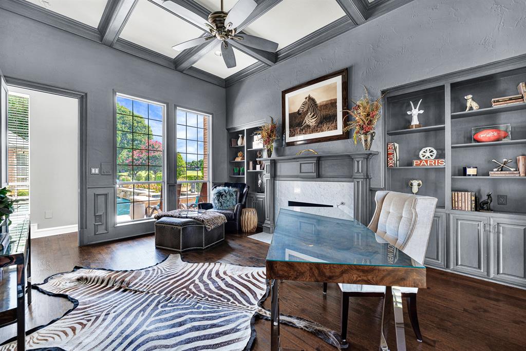 Floor-to-ceiling windows flood the study with natural light while offering direct views of the backyard pool patio. Custom built-in cabinetry provides ample storage, combining high functionality with refined executive style.