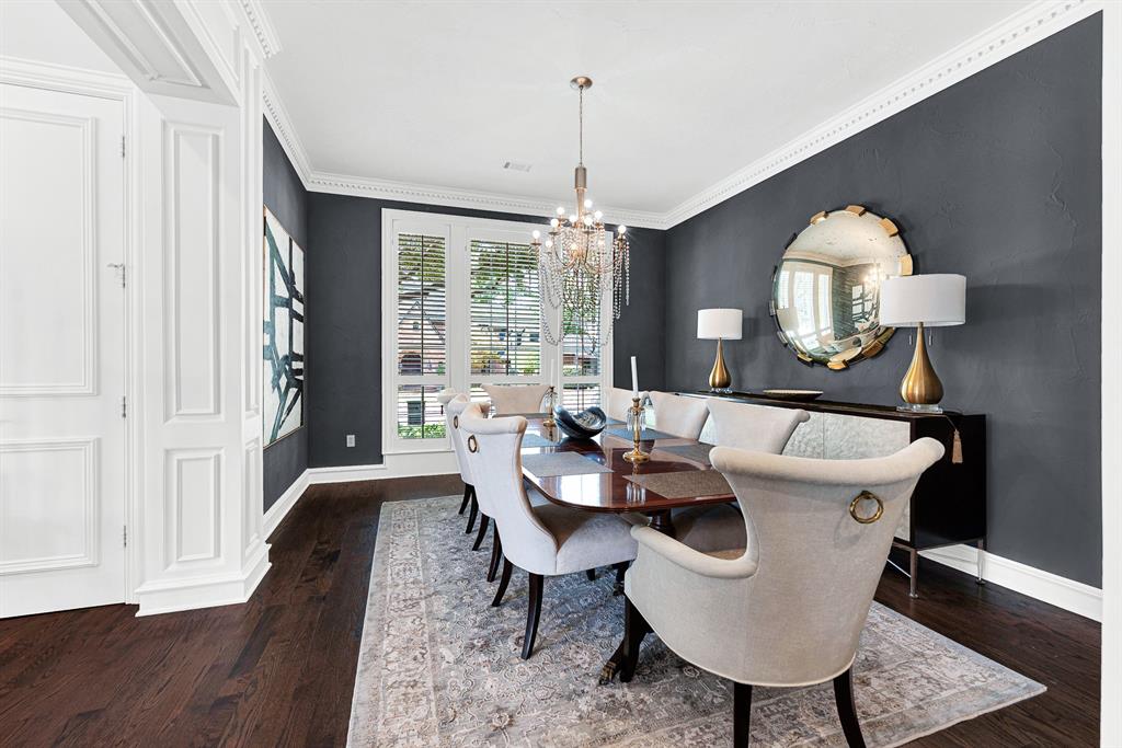 Large windows fitted with classic plantation shutters fill the dining room with soft, ambient light across rich wood flooring. It’s a stylish setting for dinner parties, where guests can gather comfortably around a large table surrounded by timeless architectural trim.
