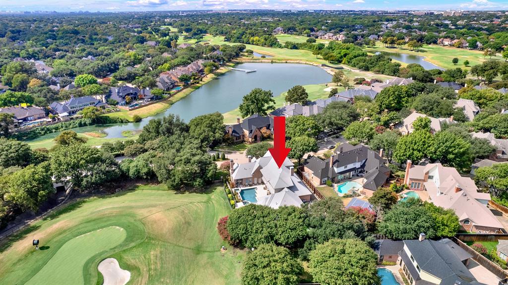 High-altitude aerial photography highlights the estate's prime positioning along the golf course green and nearby lake. Surrounded by mature tree lines and luxury properties, the home sits on an exceptionally private lot