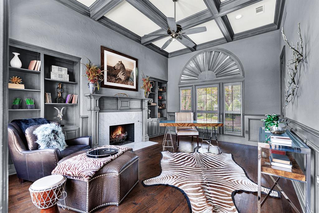 Moulded coffered ceilings, charcoal walls, and built-in shelving surround a central gas fireplace in this handsome private study that could be a fifth bedroom. It is an ideal setting for working from home or relaxing with a book by the fire.