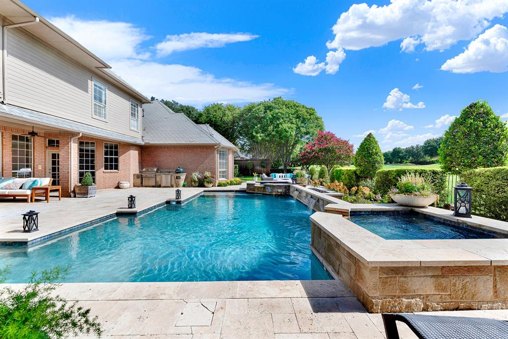 Sparkling blue waters take center stage alongside a stone-encased spa, custom water features, and manicured landscaping. Imagine spending sunny weekends splashing with family or relaxing in the warm spa under open blue skies.