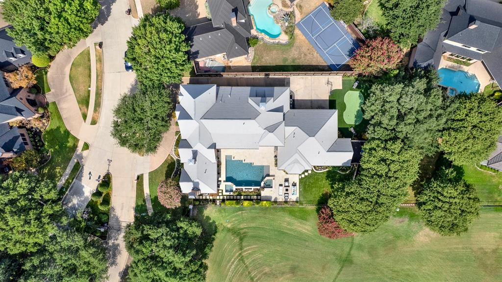 A precise top-down drone capture perfectly illustrates the property’s scale, from the intricate grey tiled roofline to the functional layout of the pool, putting green, and private circular drive. This unique perspective gives you a true appreciation for the meticulous design and expansive grounds your family will call home.