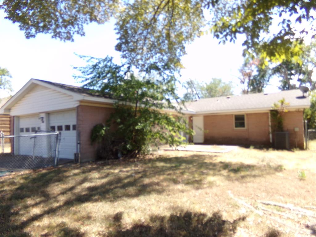Brick exterior with an attached two-car garage, white garage doors, and a patio area