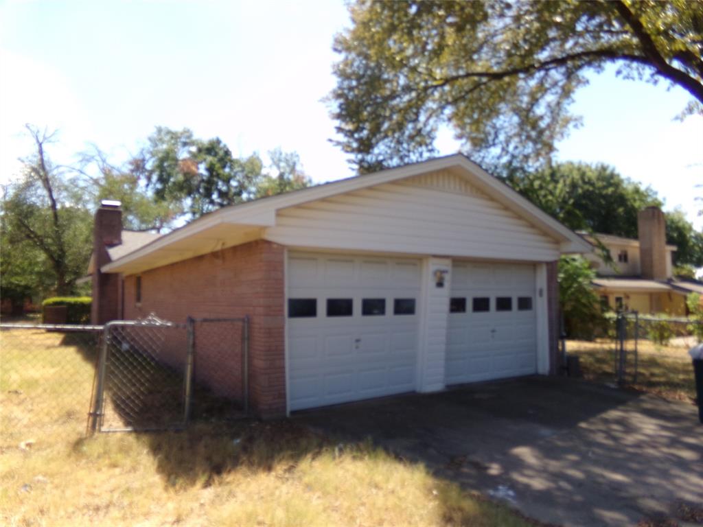 Two-car garage with white paneled doors, brick exterior, and a side chimney