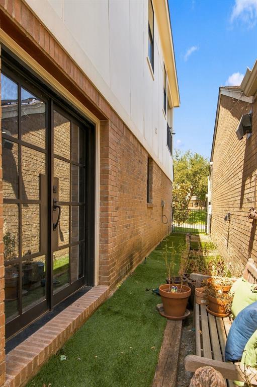 Brick and siding exterior featuring a glass-paneled entry door, a brick threshold, and artificial turf landscaping