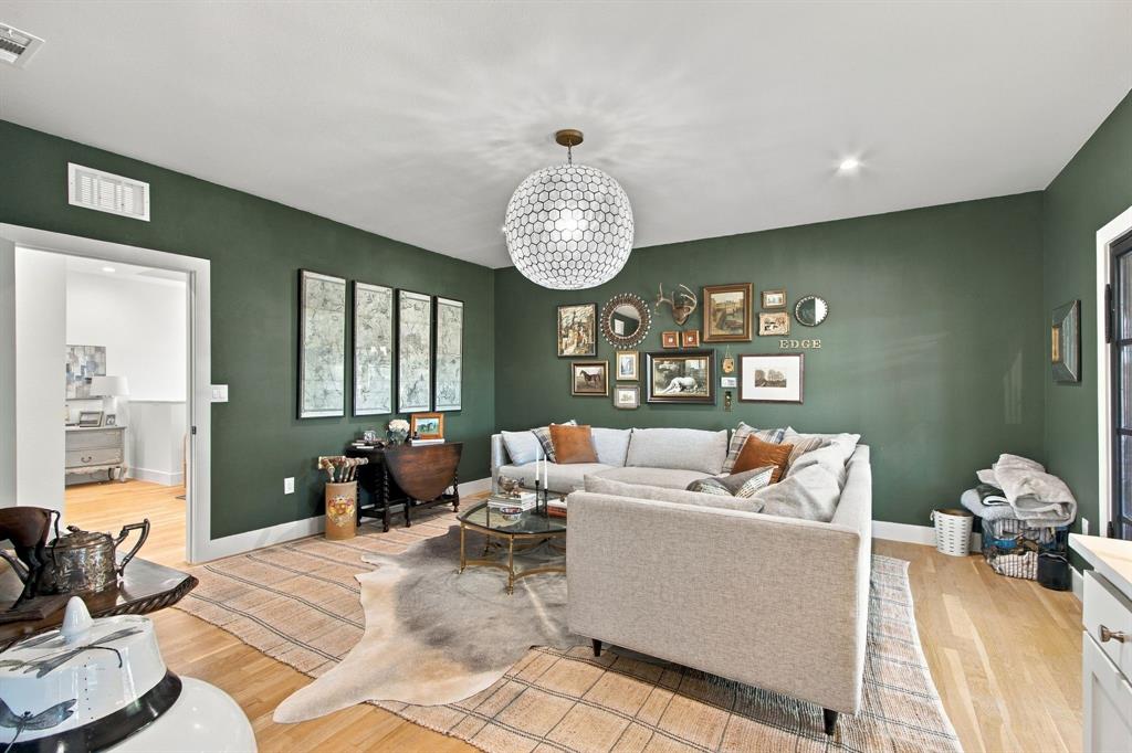 Light wood-finish flooring, recessed lighting, and a modern ceiling fixture illuminate this space with green walls