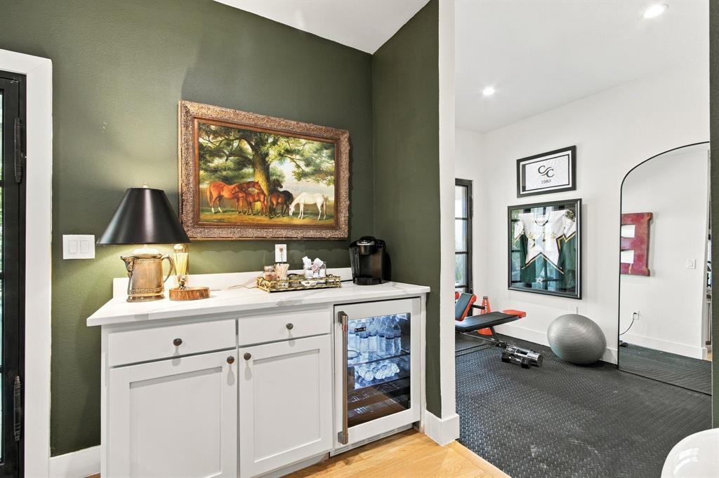 Built-in cabinetry with a beverage refrigerator, light-toned countertops, and wood-finish flooring