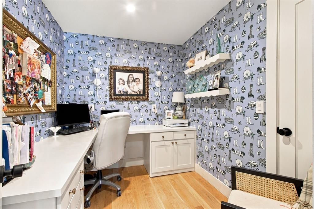 Built-in desk with cabinetry, wood-finish flooring, recessed lighting, white interior door with matte black hardware, and two white floating shelves