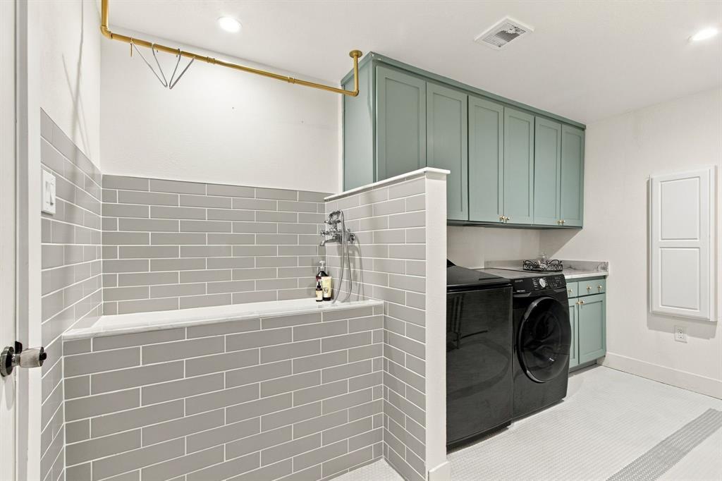 Utility room featuring a tiled dog washing station with an overhead drying rack, custom cabinetry, a built-in sink, and tile flooring