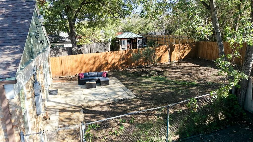 Expansive backyard featuring a new privacy fence, mature trees, and a spacious patio area