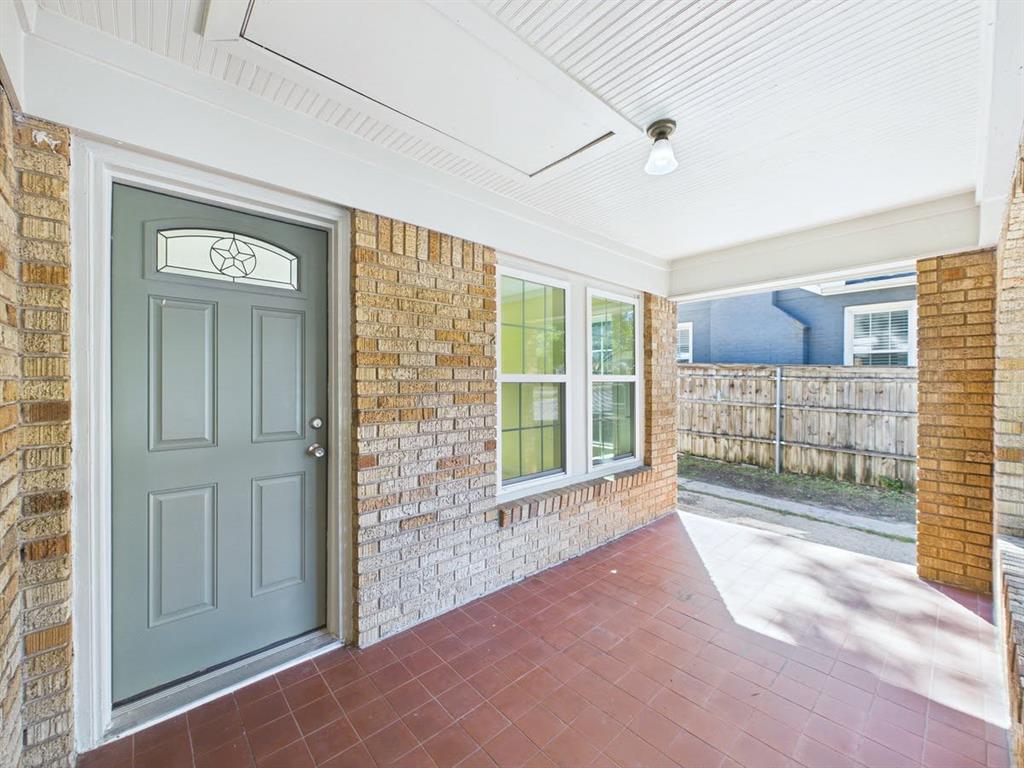 Covered porch with brick siding, a paneled entry door with decorative glass insert, and a tiled floor