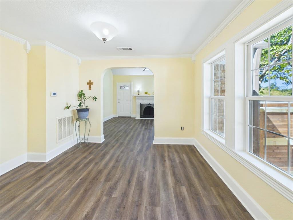 Wood-finish flooring, white trim, crown molding, double-hung windows, and a ceiling-mounted light fixture