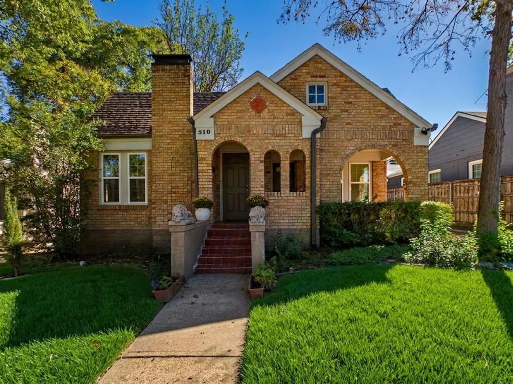 Brick exterior with a prominent brick chimney, arched entry, covered porch, and gabled roofline