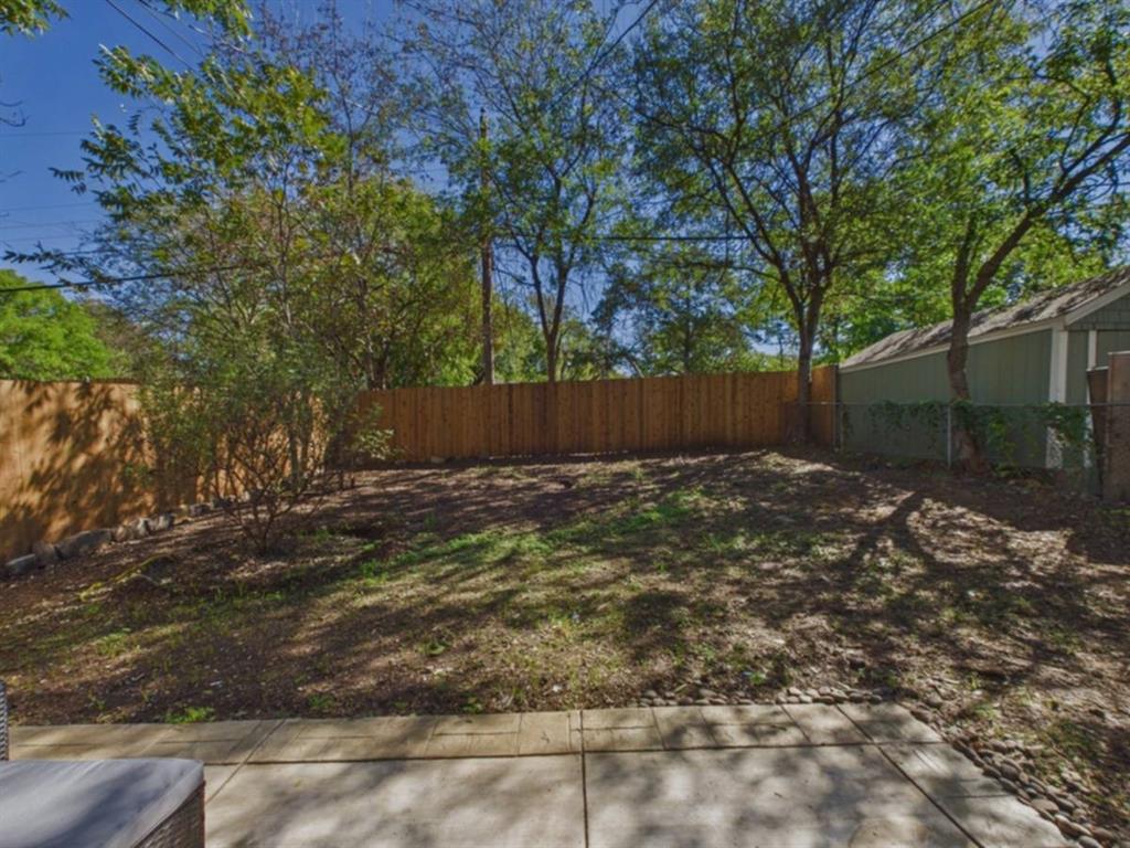Expansive outdoor space featuring a concrete patio, wood privacy fencing, and mature trees