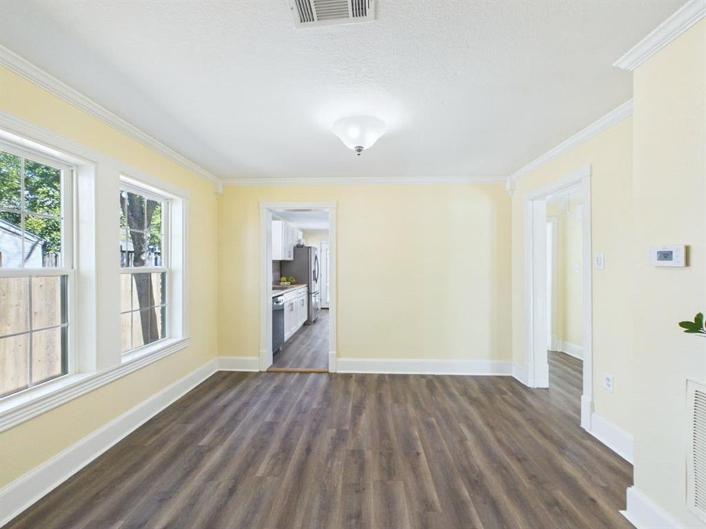 Spacious room featuring wood-finish flooring, multiple windows, and crown molding