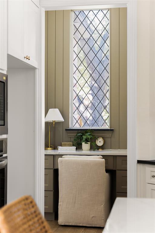 Dedicated desk nook adjacent to the kitchen combines built-in cabinetry and workspace with a striking leaded-glass window, creating a functional spot for work, organization, or household planning.