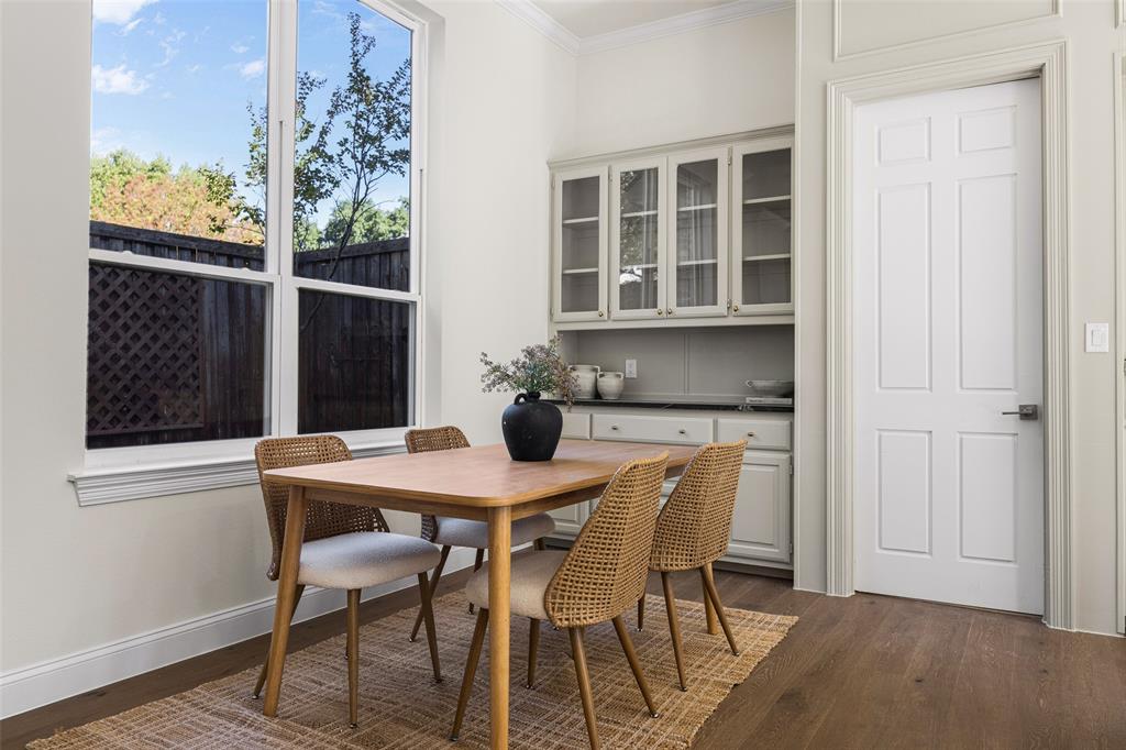 Light-filled breakfast area with oversized windows, warm wood flooring, and extensive glass-front built-in cabinetry offering additional display space, storage, and serving functionality.