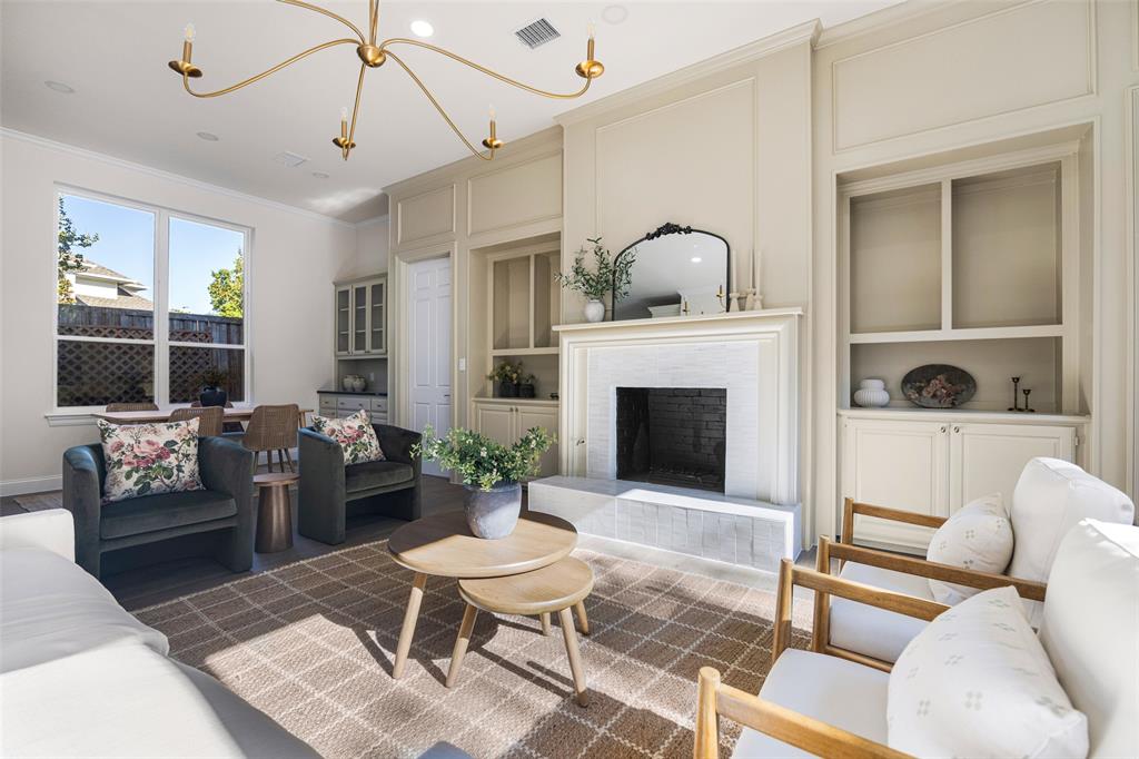 Symmetrical built-ins, statement chandelier, a generous seating area, and backyard-facing windows all add the the inviting feel of the living space.