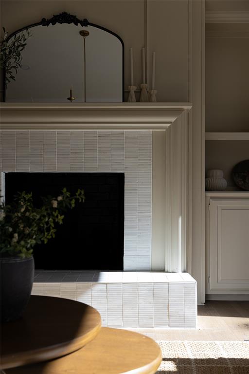 Architectural fireplace detail showcases the layered millwork, textured tile surround, raised hearth, and adjacent built-in cabinetry that give the room a custom finish