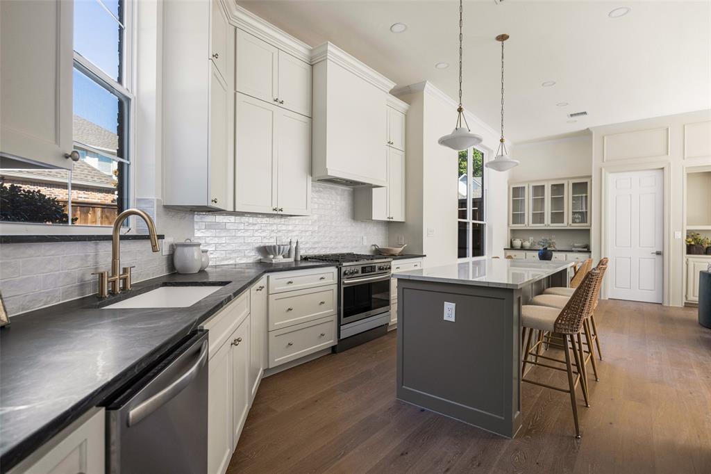 Oversized island with seating, two-tone cabinetry, extensive storage, gas cooking, pendant lighting, and generous workspace for both everyday use and entertaining make this kitchen both fabulous and functional.