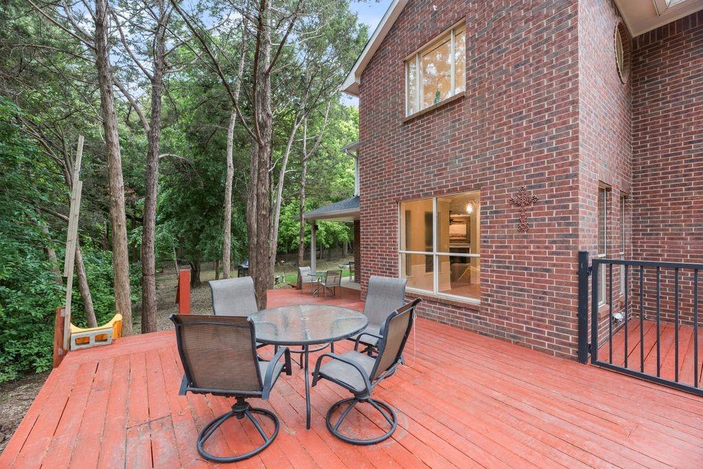 Spacious backyard deck surrounded by mature trees offers a peaceful, private setting perfect for outdoor dining, entertaining, or simply relaxing at home.