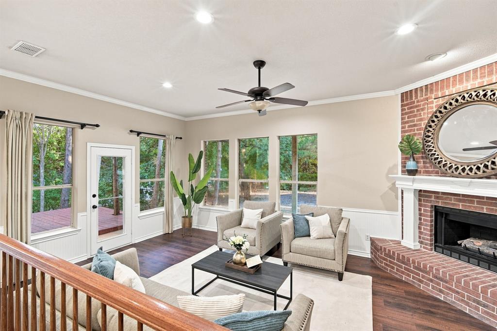 Charming sitting room with a vaulted ceiling, ceiling fan, cozy brick fireplace, and French doors opening to the backyard, a perfect spot to unwind.