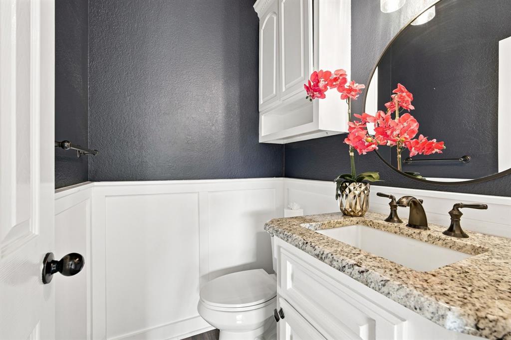 Stylish powder bath accented with white wainscoting and a bold dark wall color.