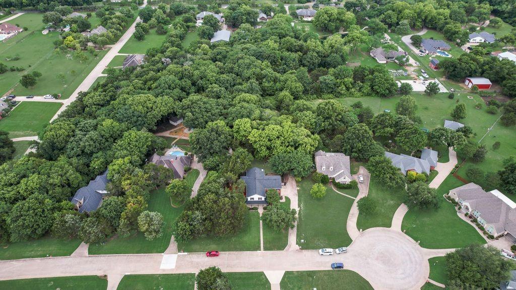 Aerial view highlights the home’s beautiful setting, mature trees, spacious lot, and peaceful neighborhood surroundings