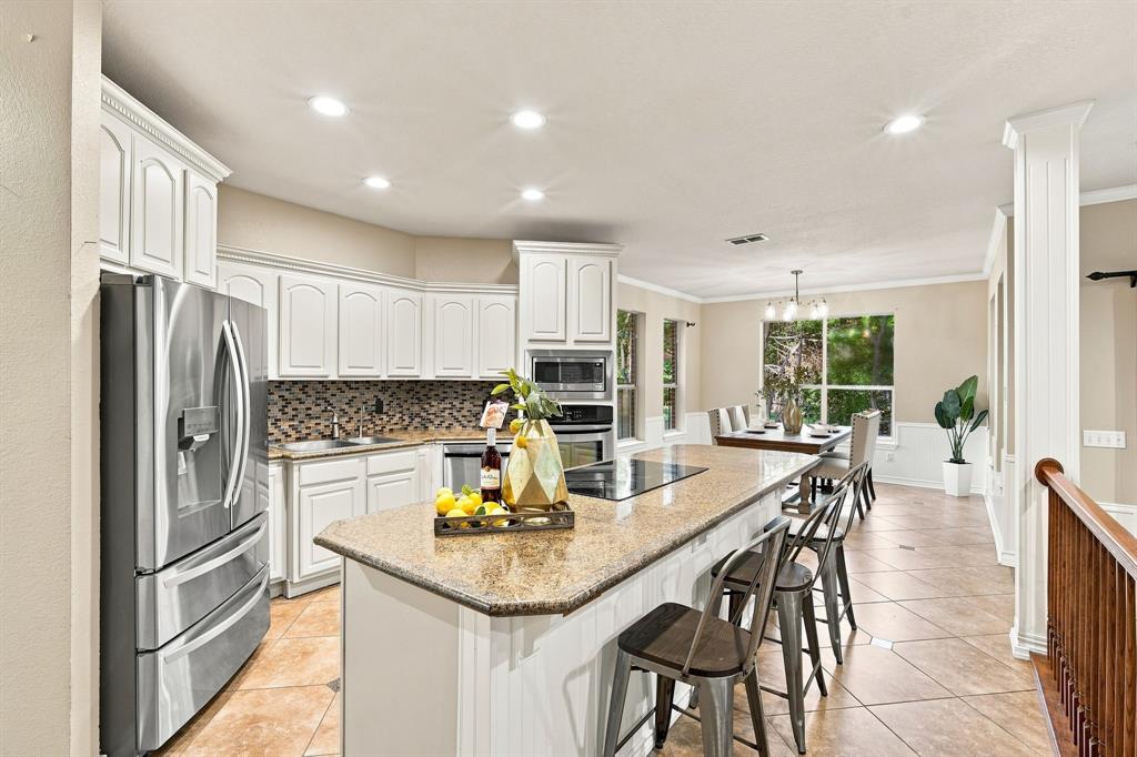 Beautifully appointed kitchen with crisp white cabinetry, a spacious island with a cooktop, and a stylish tile backsplash.