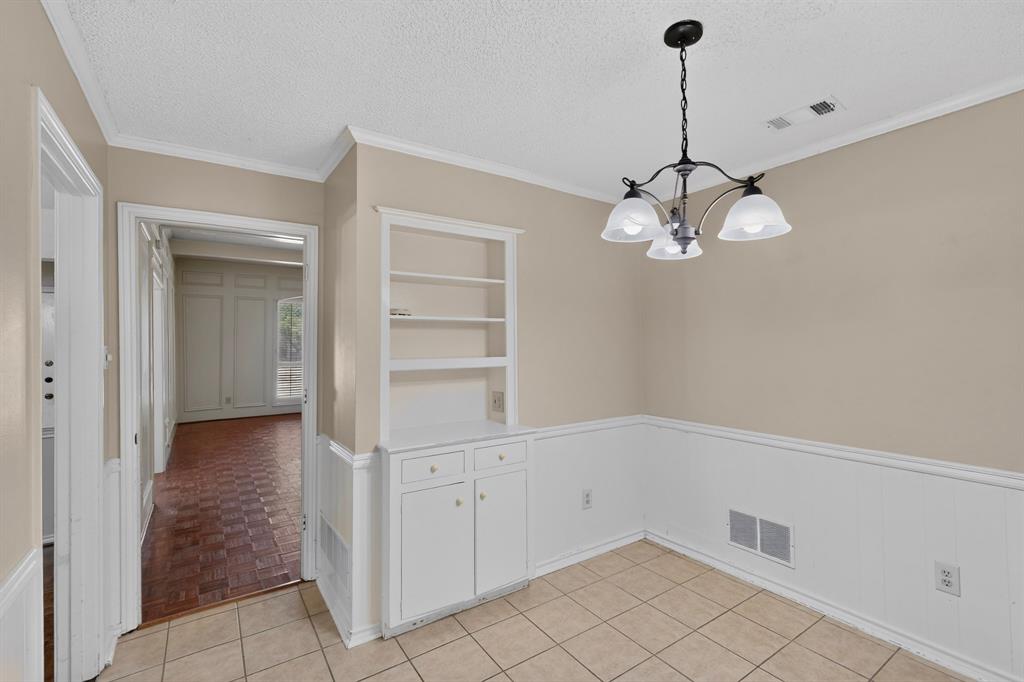 Tile flooring, a built-in cabinet with shelving, wainscoting, and a chandelier