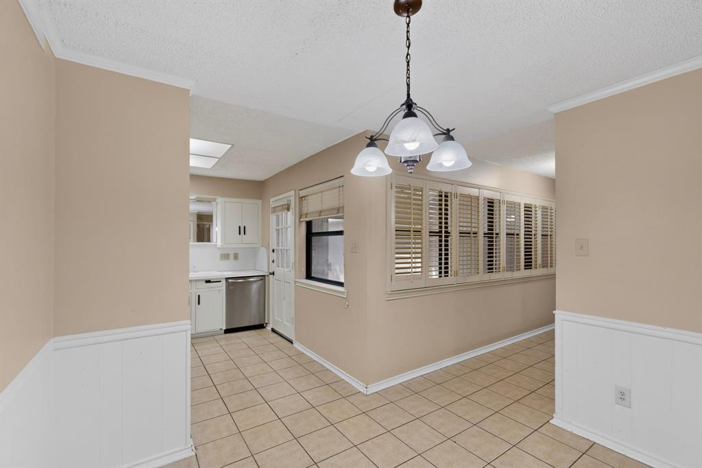Tiled flooring, wainscoting, wood-finish plantation shutters, ceiling-mounted light fixture, and white cabinetry