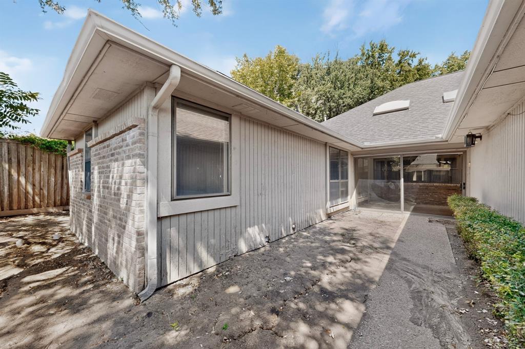 Exterior featuring brick and vertical panel siding, a screened-in patio, concrete pathway, and mature landscaping
