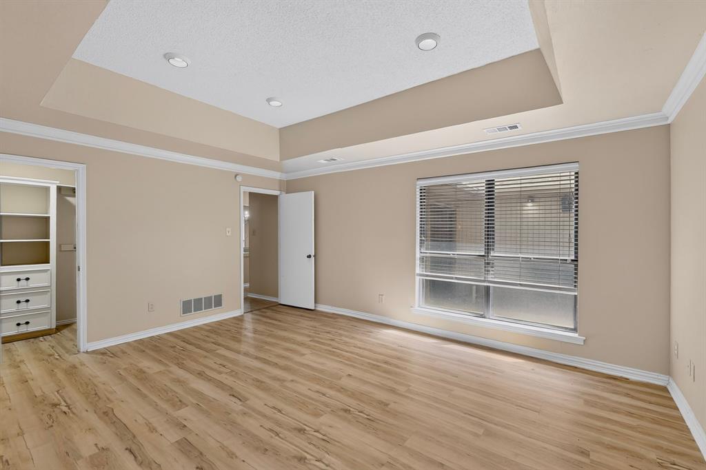 Recessed lighting, crown molding, a tray ceiling, wood-finish flooring, and built-in closet shelving