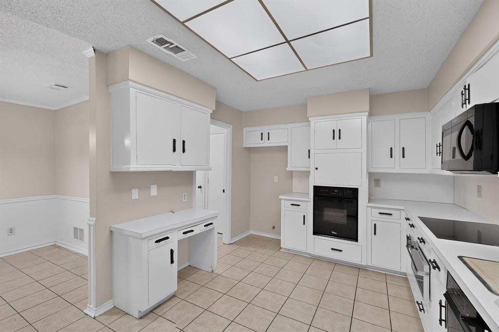 Kitchen featuring white cabinetry, integrated black oven, and white countertops