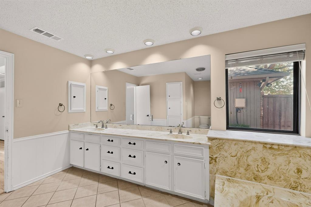 Dual vanity with white cabinetry, integrated sinks, an expansive mirror, and recessed lighting